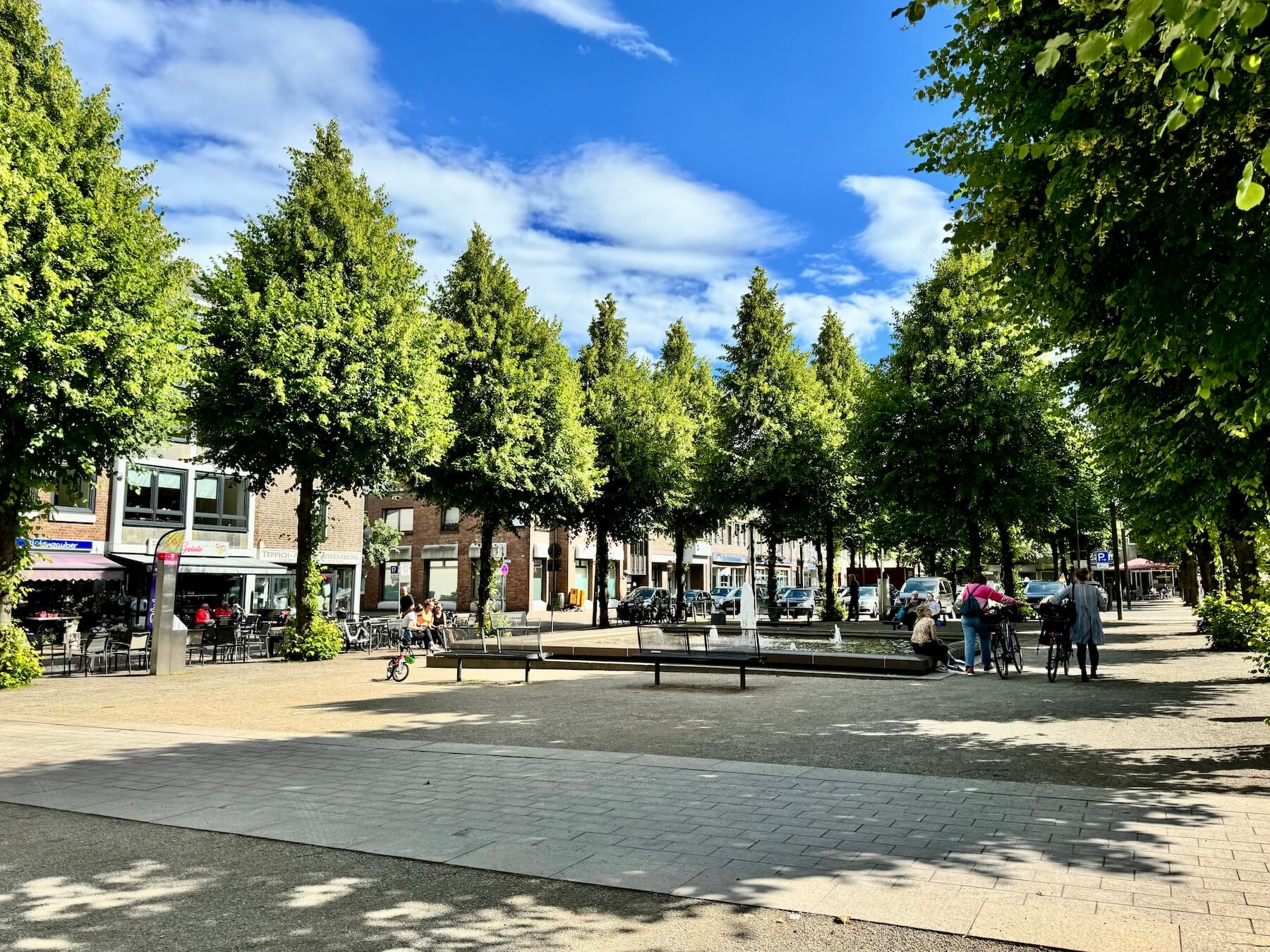 Bäume und ein Platz, im Hintergrund Häuser. Die Große Straße in Ahrensburg, Schauplatz der Velolution
