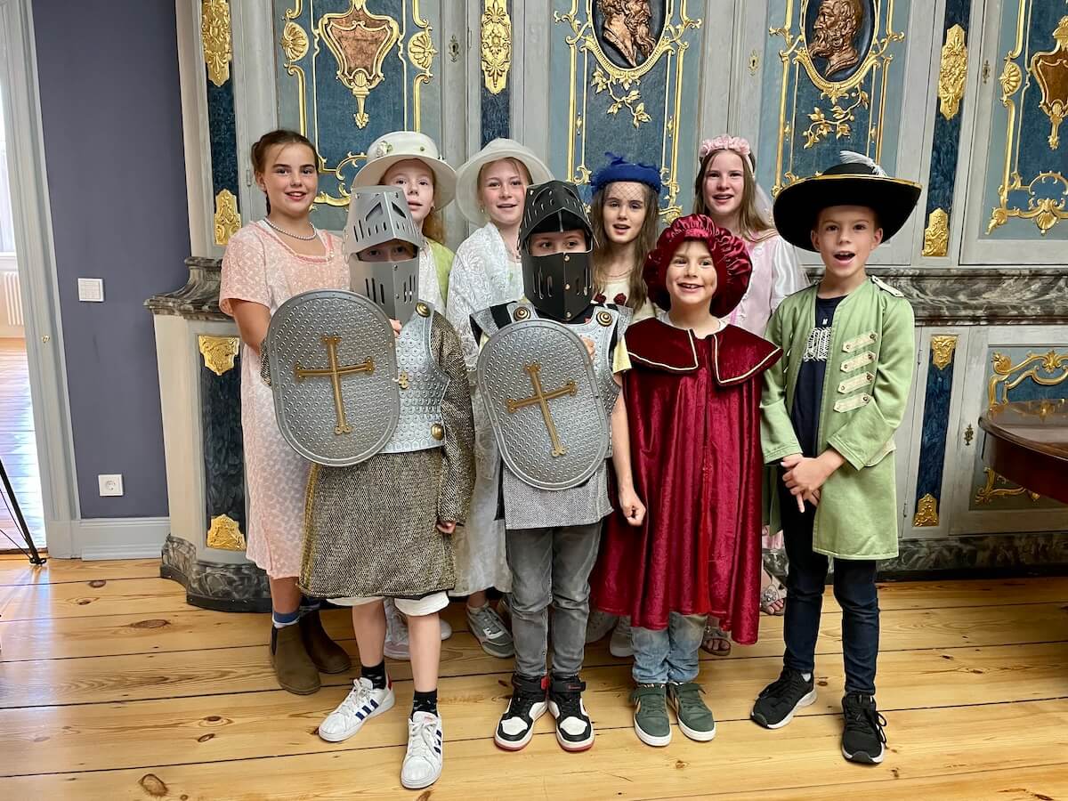 Eine Gruppe verkleideter Kinder vor einem prunkvollen Schrank