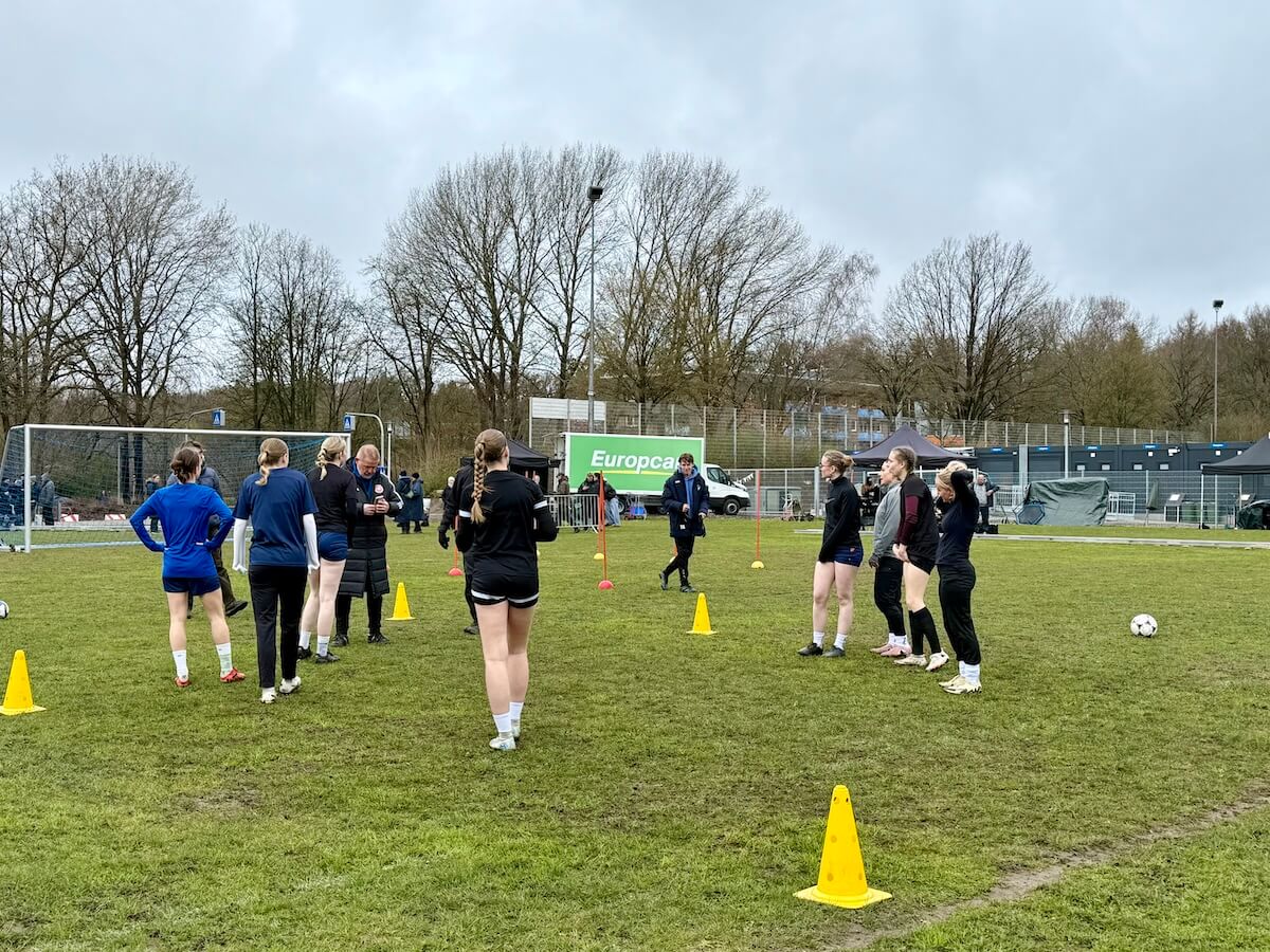 Fußballerinnen auf dem Platz, im Hintergrund ein LKW