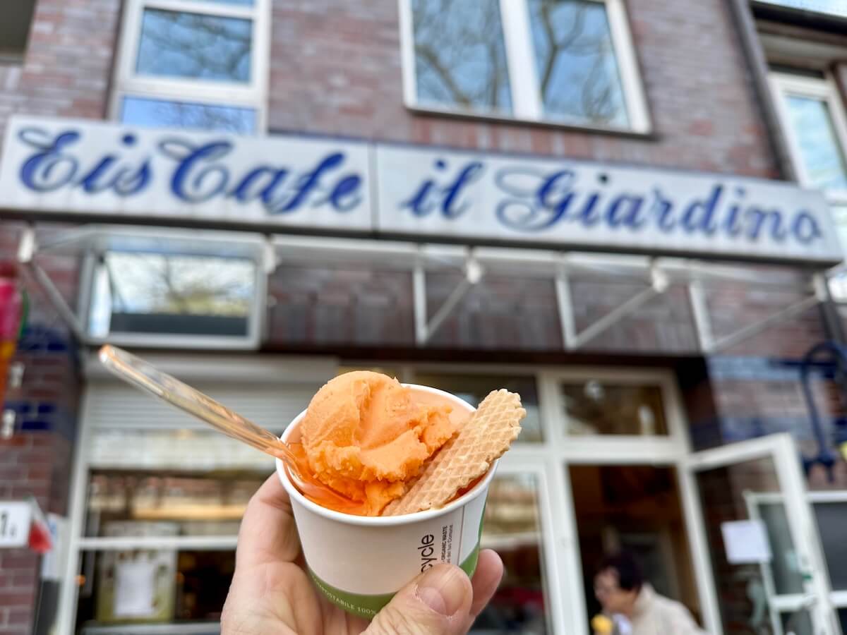 Ein Becher mit Orangeneis, im HIntergrund der Schriftzug EisCafé Il Giardino