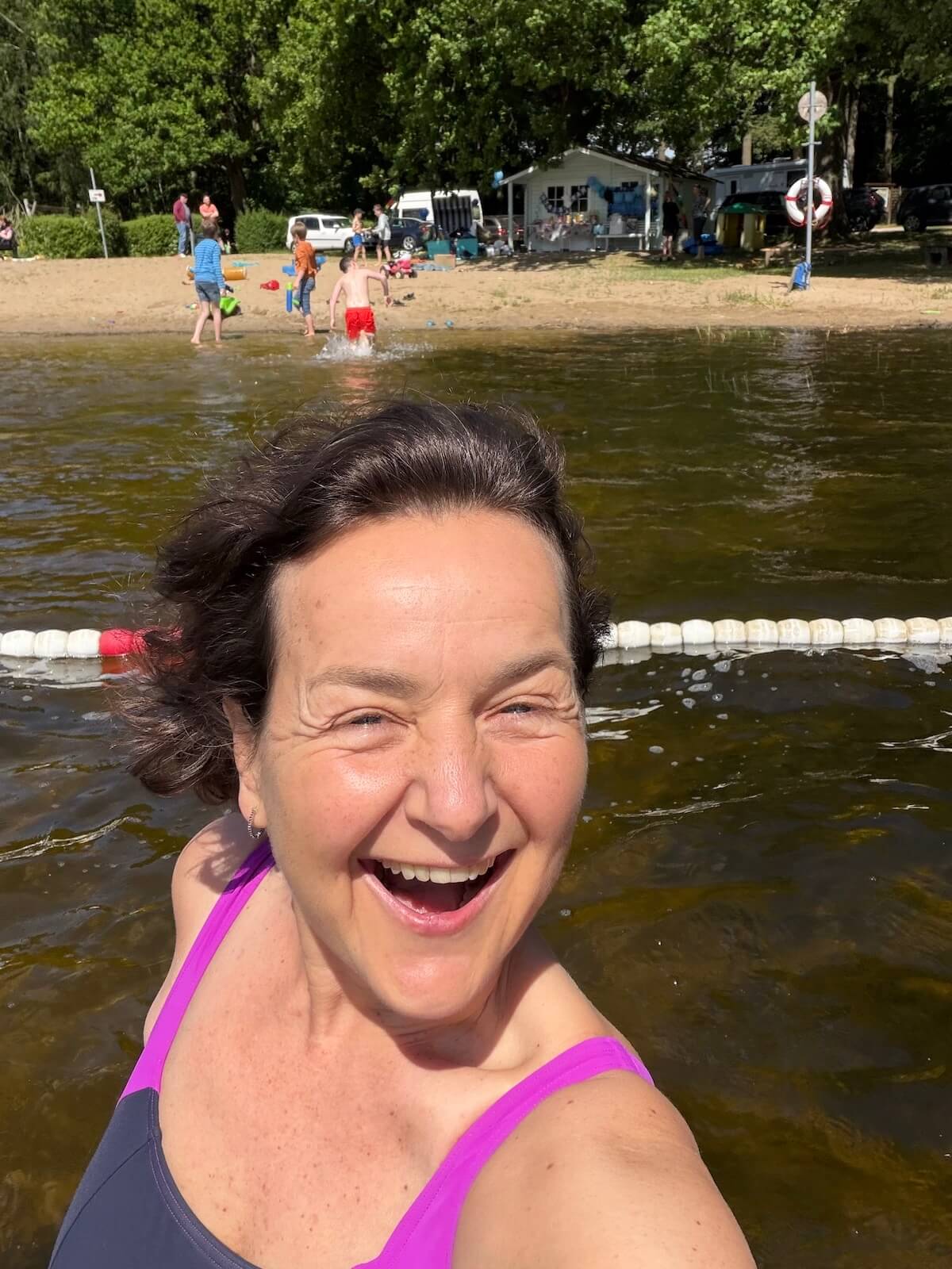 Eine Frau im Wasser, im Hintergrund ein Strand