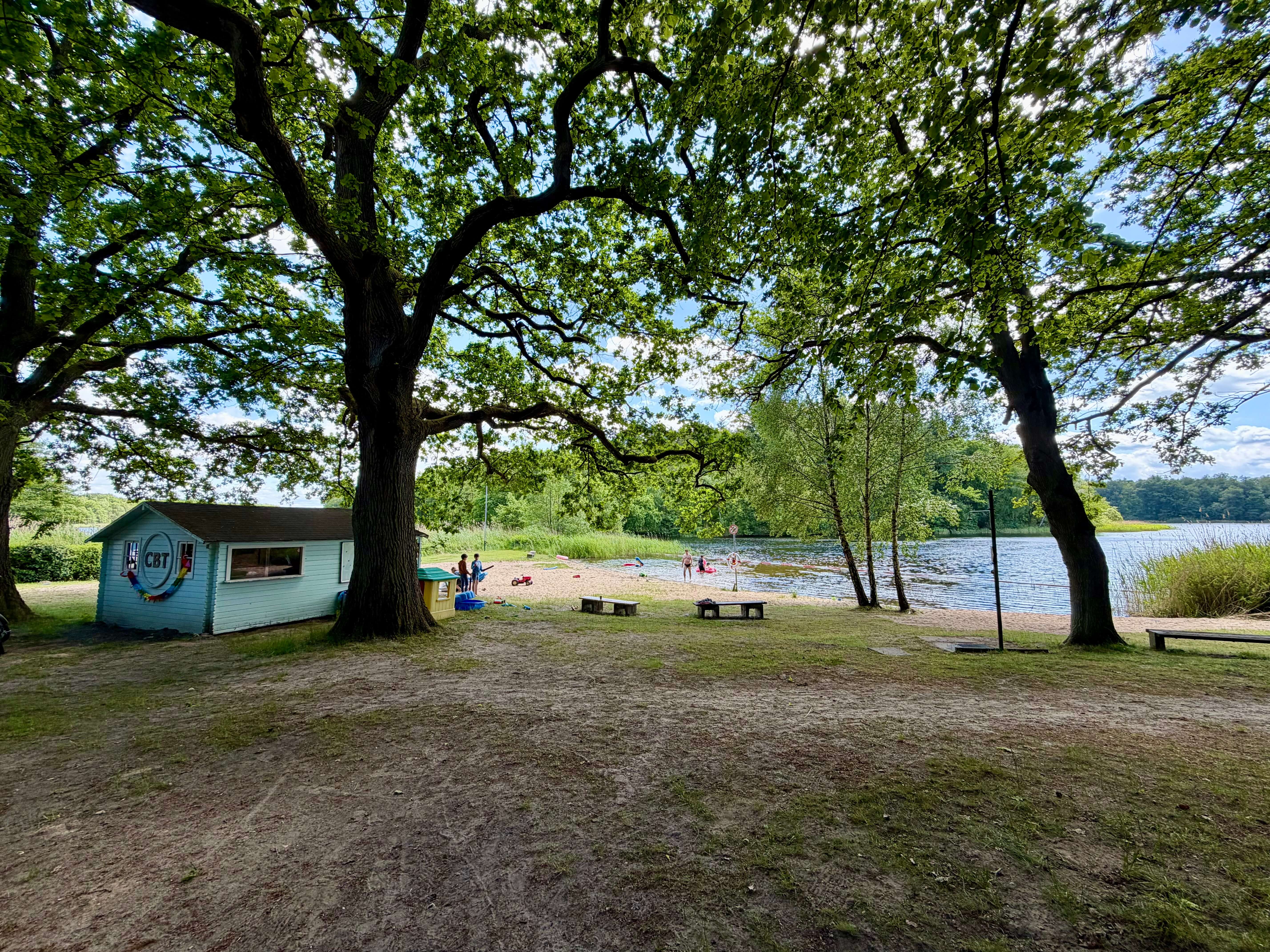 Blick zu einem Strand mit Bäumen, an dem eine kleine Holzhütte steht