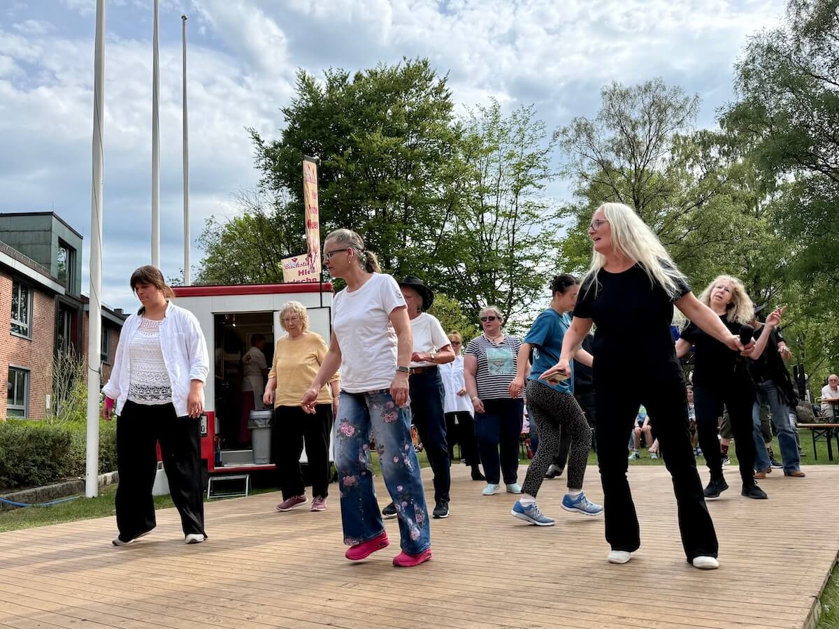 Mehrere Menschen tanzen Linedance auf einer Bühne