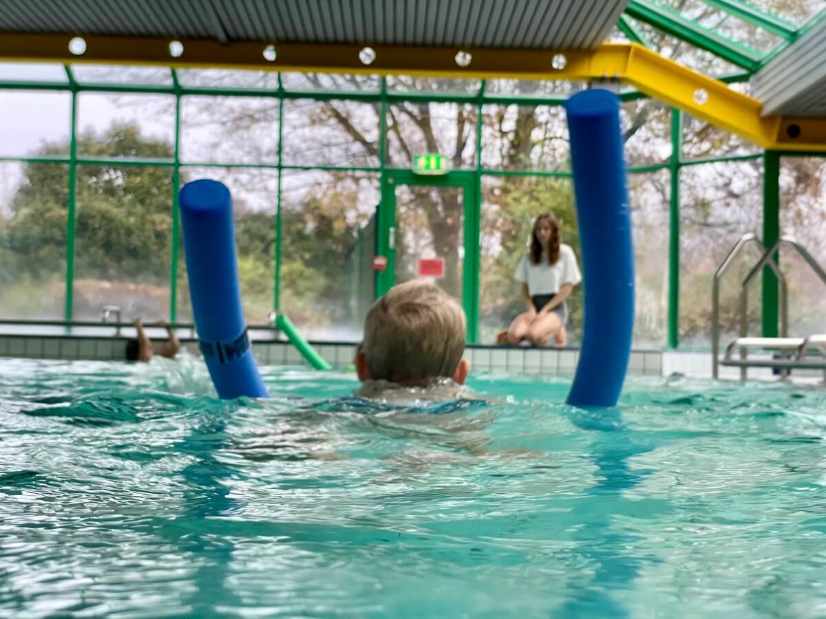 Kinderschwimmen. Ein Kind mit einer Poolnudel im Wasser