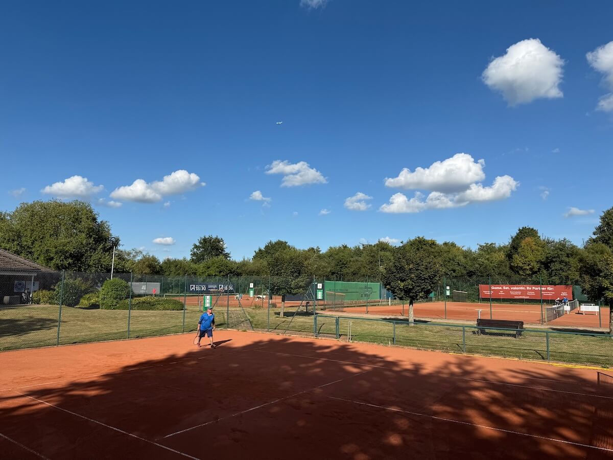 Tennisplätze beim SSC Hagen Ahrensburg. Blauer Himmel, grüne Bäume.