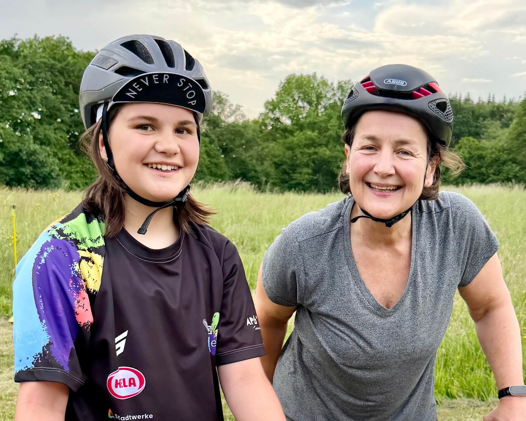 Zwei Frauen mit Fahrradhelmen auf im Grünen