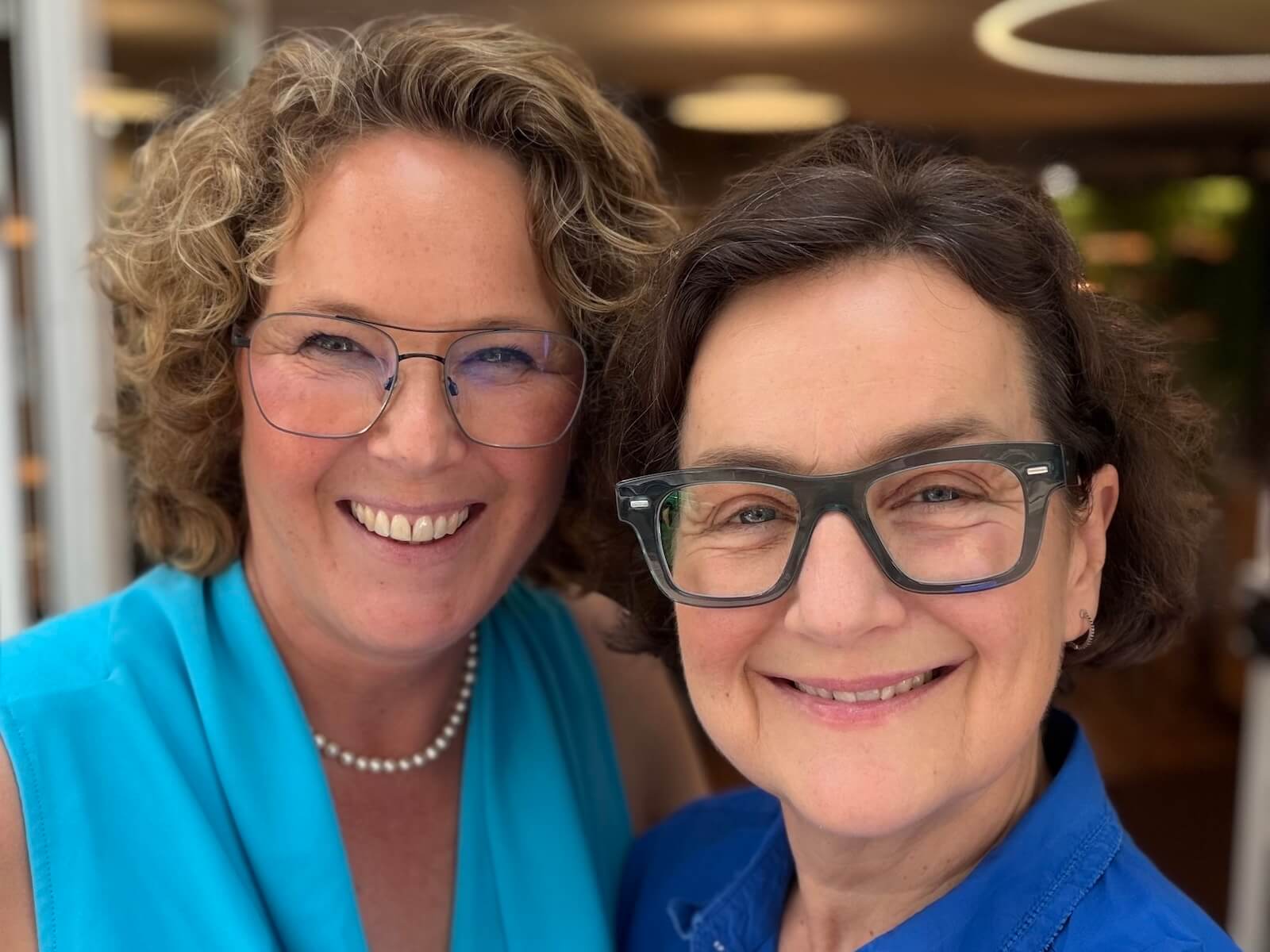 Zwei Frauen mit Brillen lachen in die Kamera