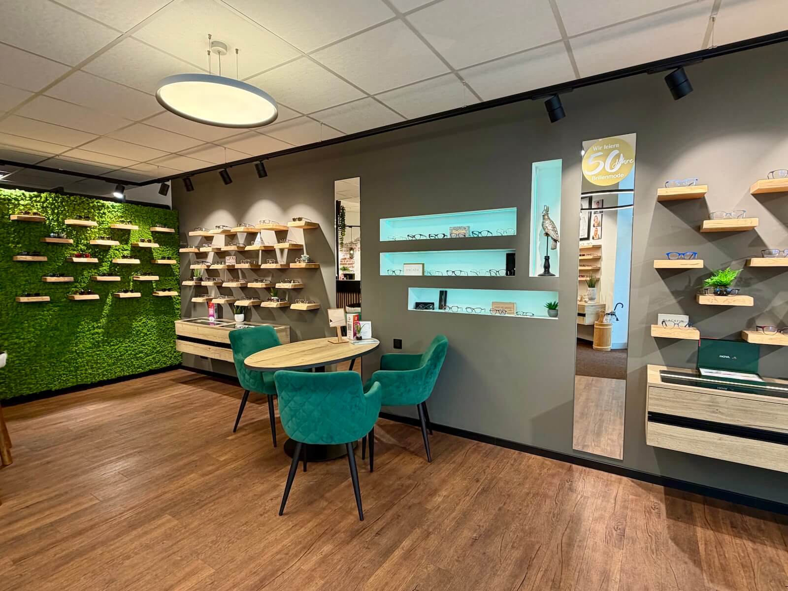 Optikergeschaft, Sitzecke mit grünen Stühlen und Holztisch