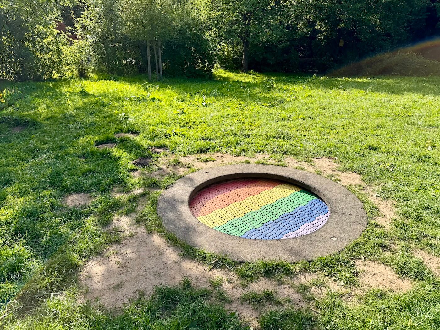 Buntes Trampolin in den Boden eingelassen auf einer Wiese