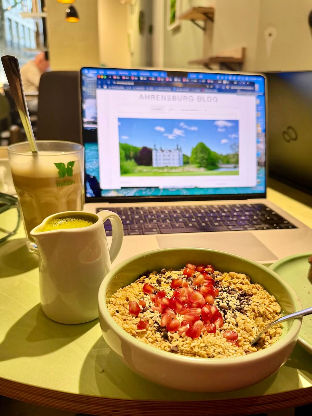 Ein Laptop auf einem Tisch, davor Kaffee und ein Müsli